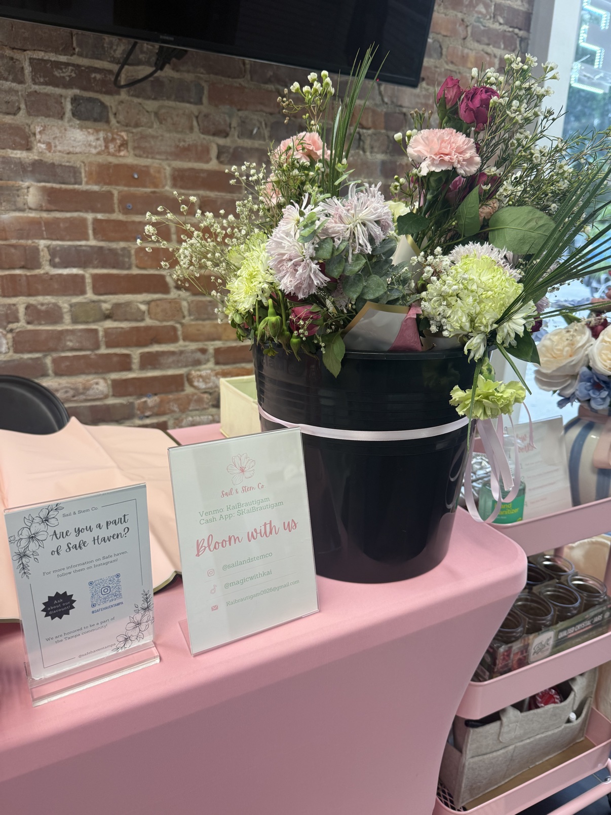 Pastel flowers displayed in a black bucket on the bloom bar
