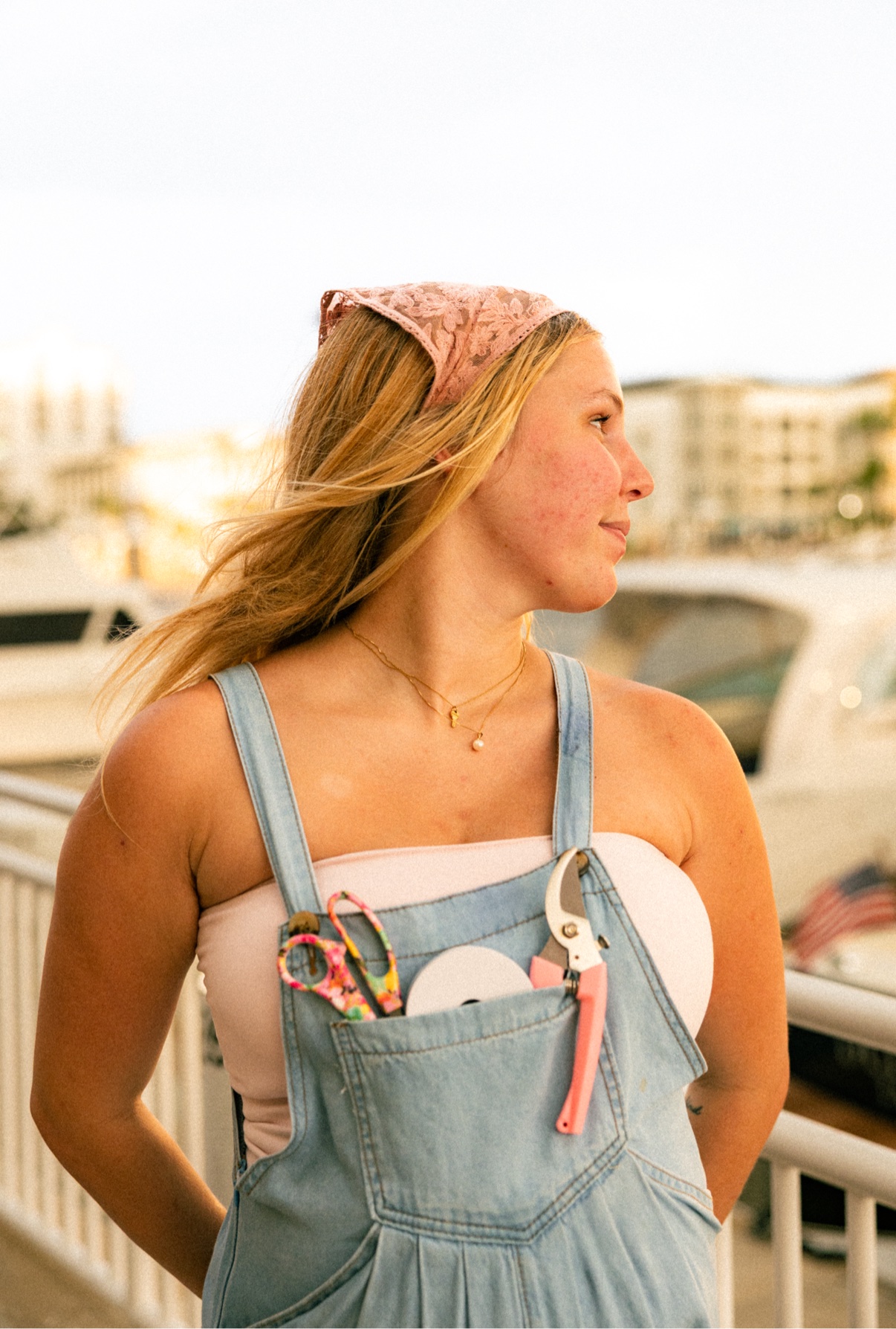 Kai in denim overalls with floral shears tucked in her pocket