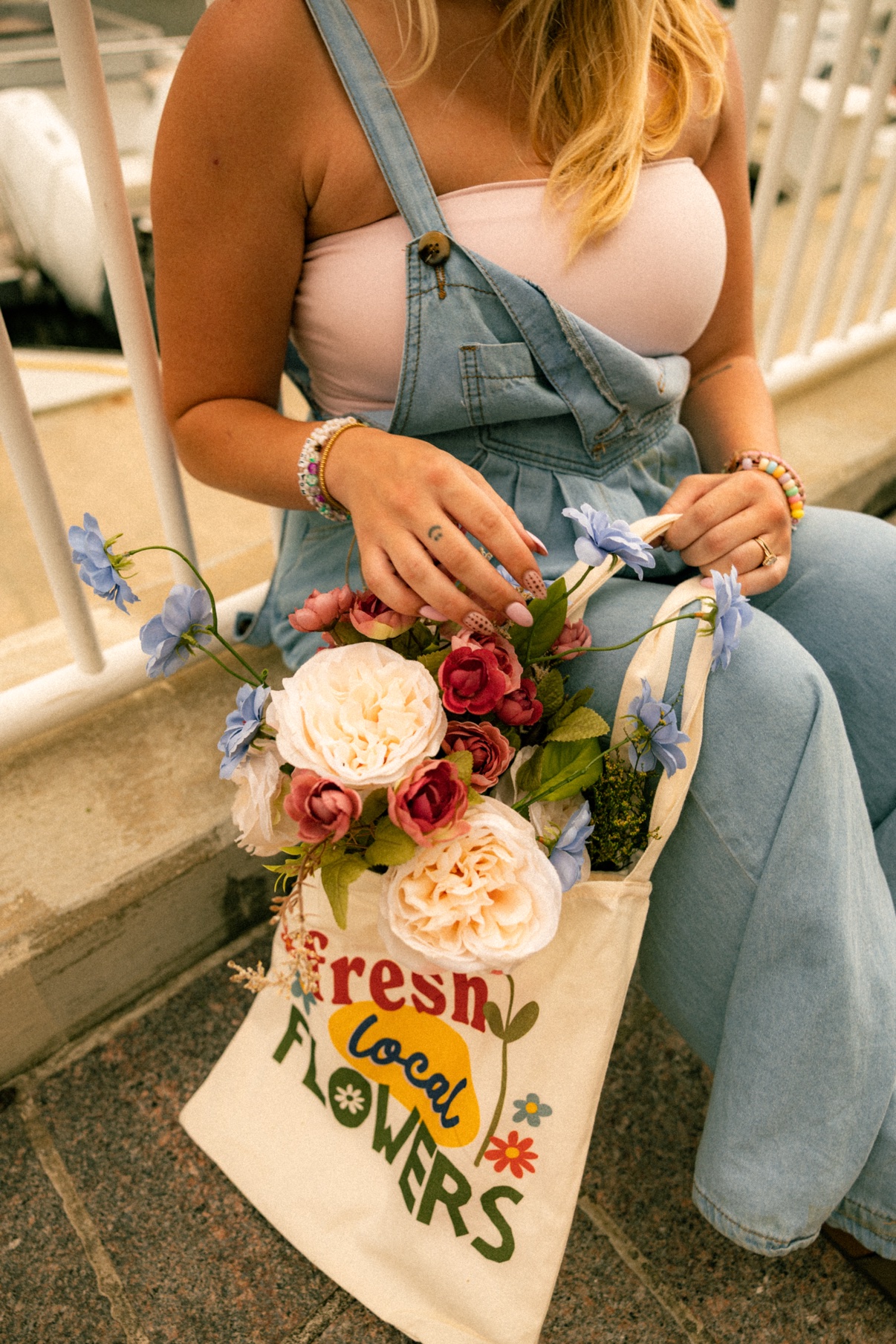 Kai sitting with her tote bag overflowing with fresh flowers