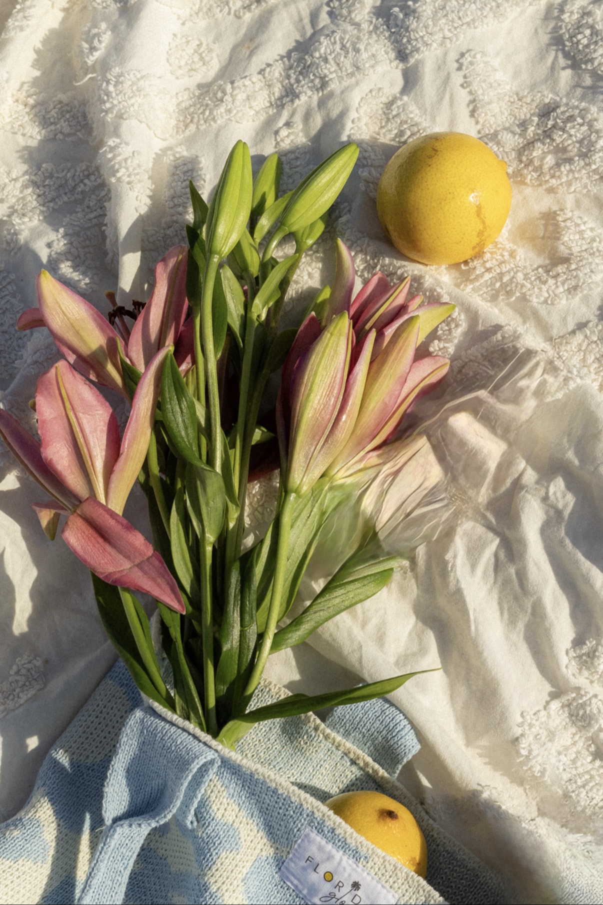 Pink lilies and lemons styled on an embroidered picnic cloth