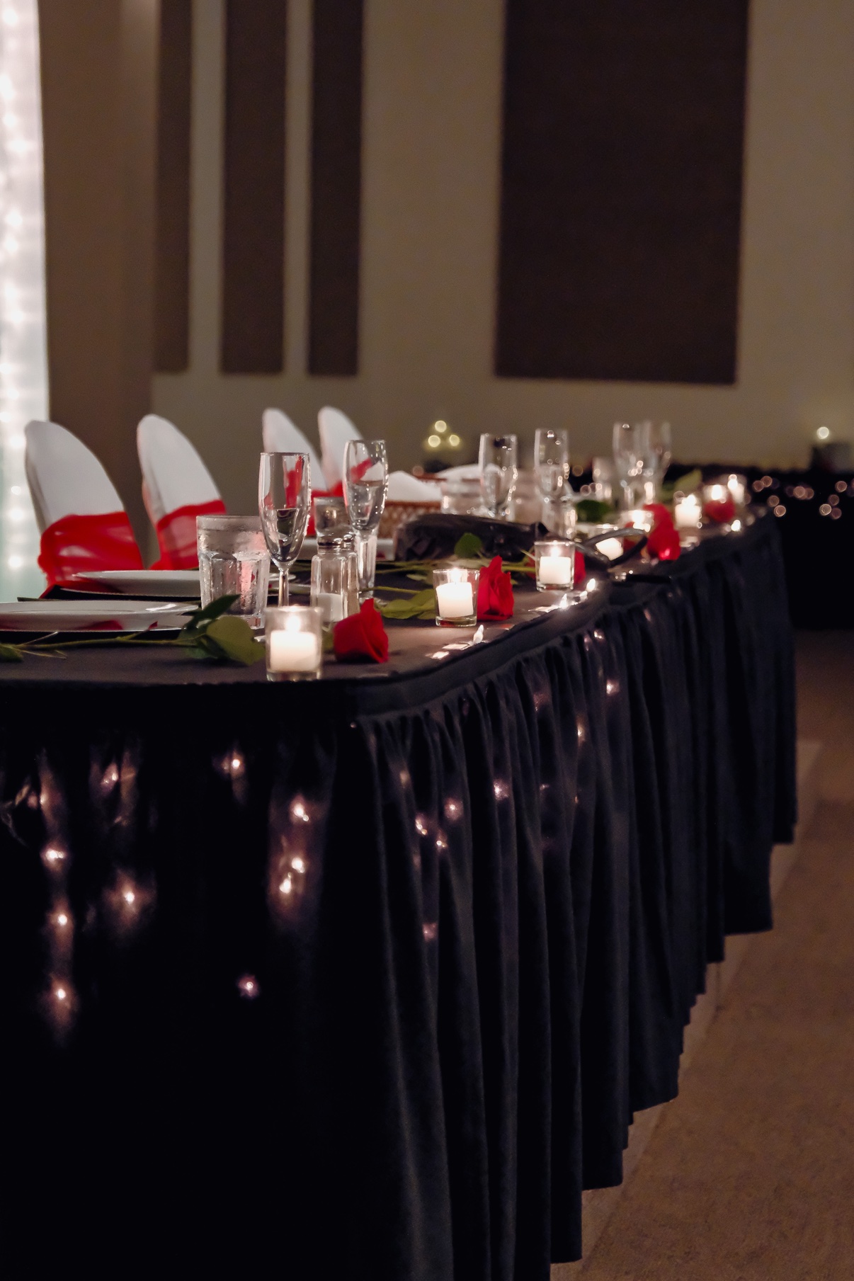 Candlelit reception table decorated with red roses and black linens