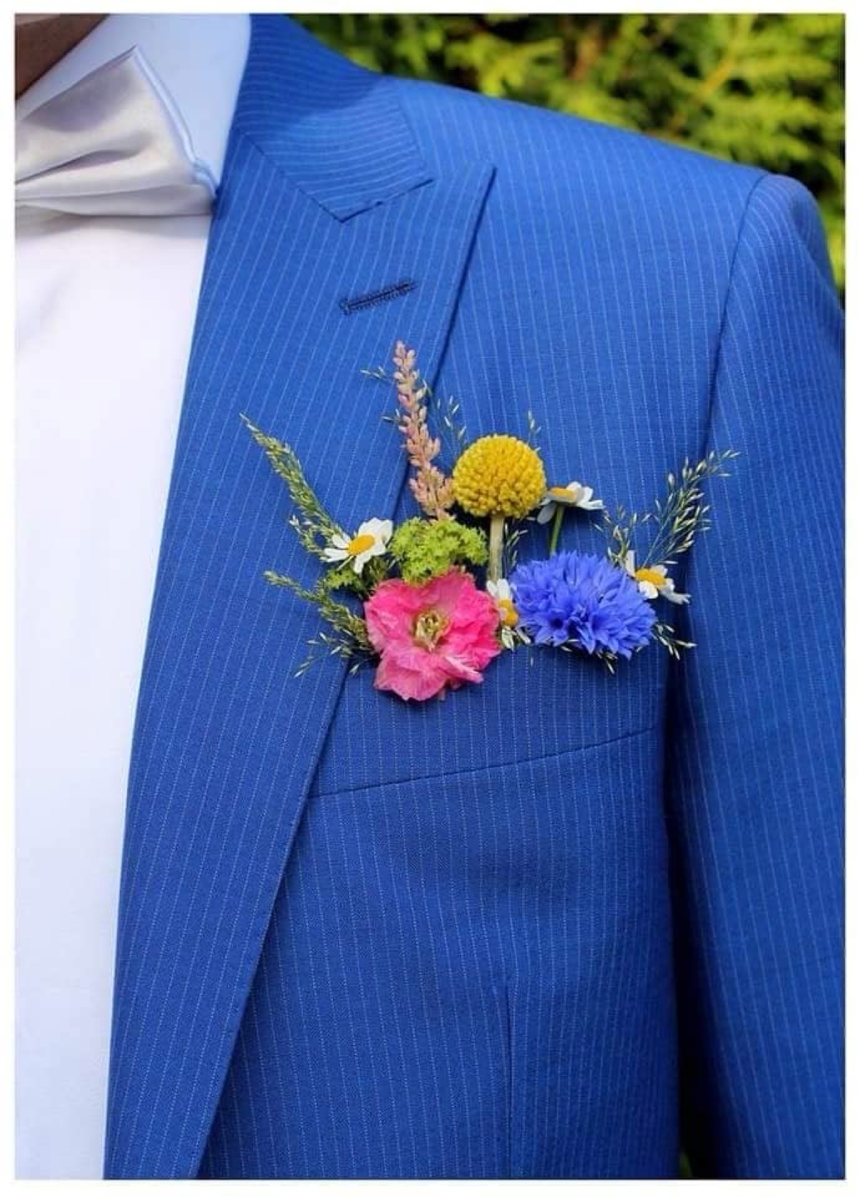 Colorful floral boutonnière pinned to a blue suit jacket